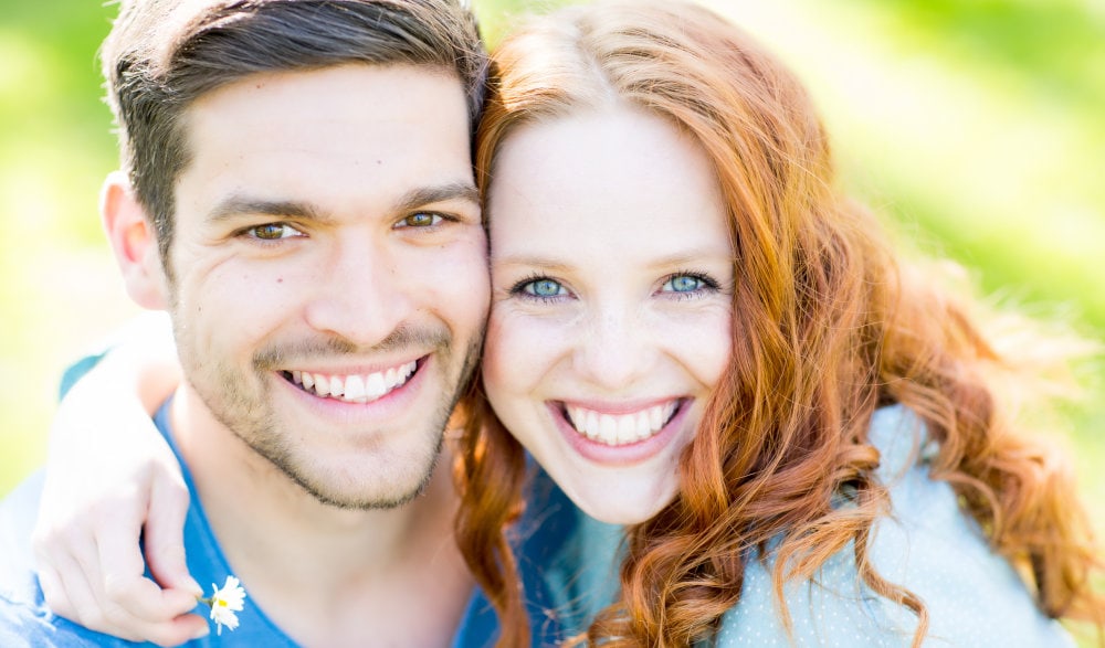 Glückliches Paar mit schönen Zähnen nach Behandlung in einer Zahnarztpraxis in Spandau